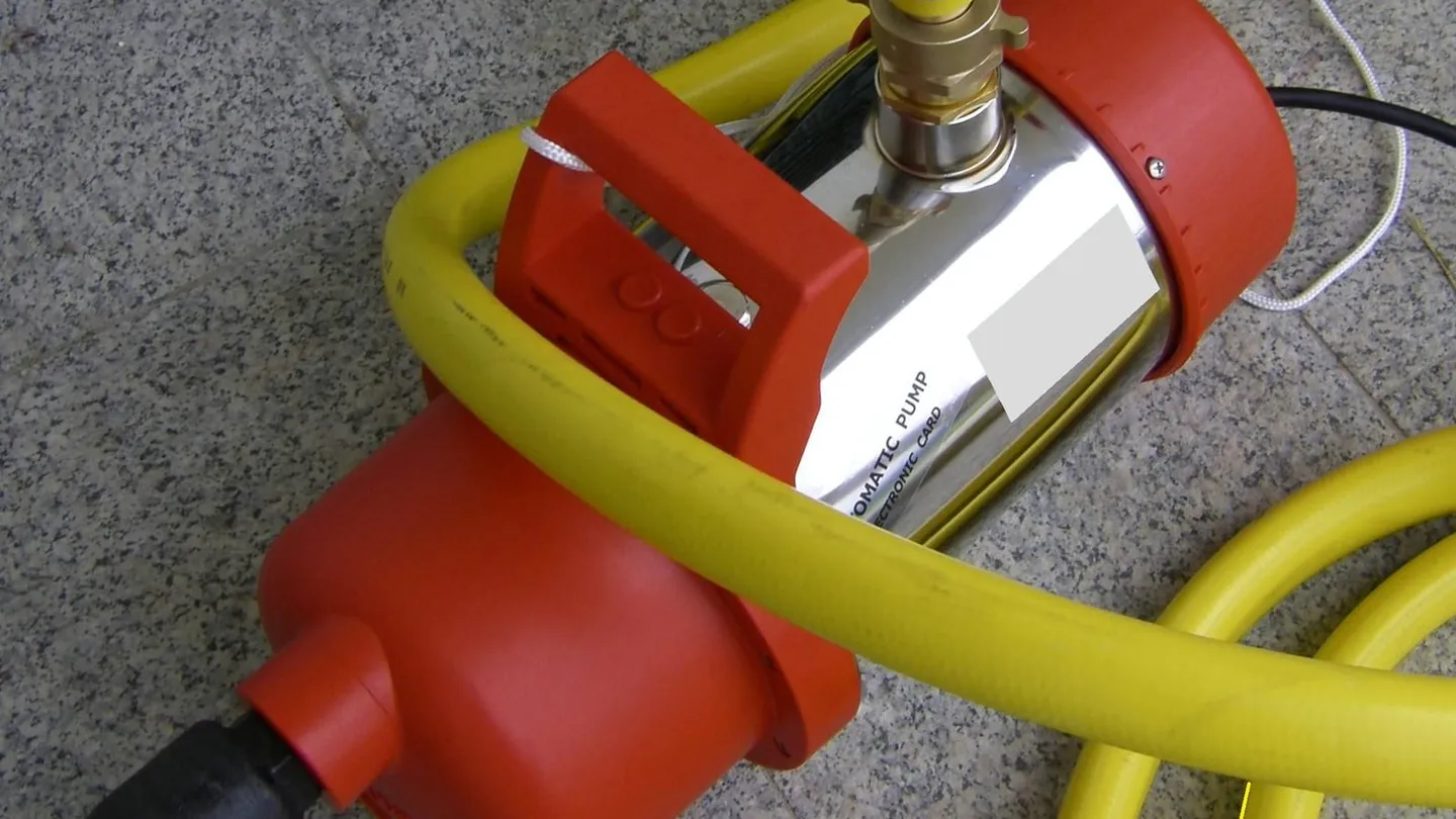 Bomba sumergible de acero inoxidable con su manguera amarilla, fuera del agua