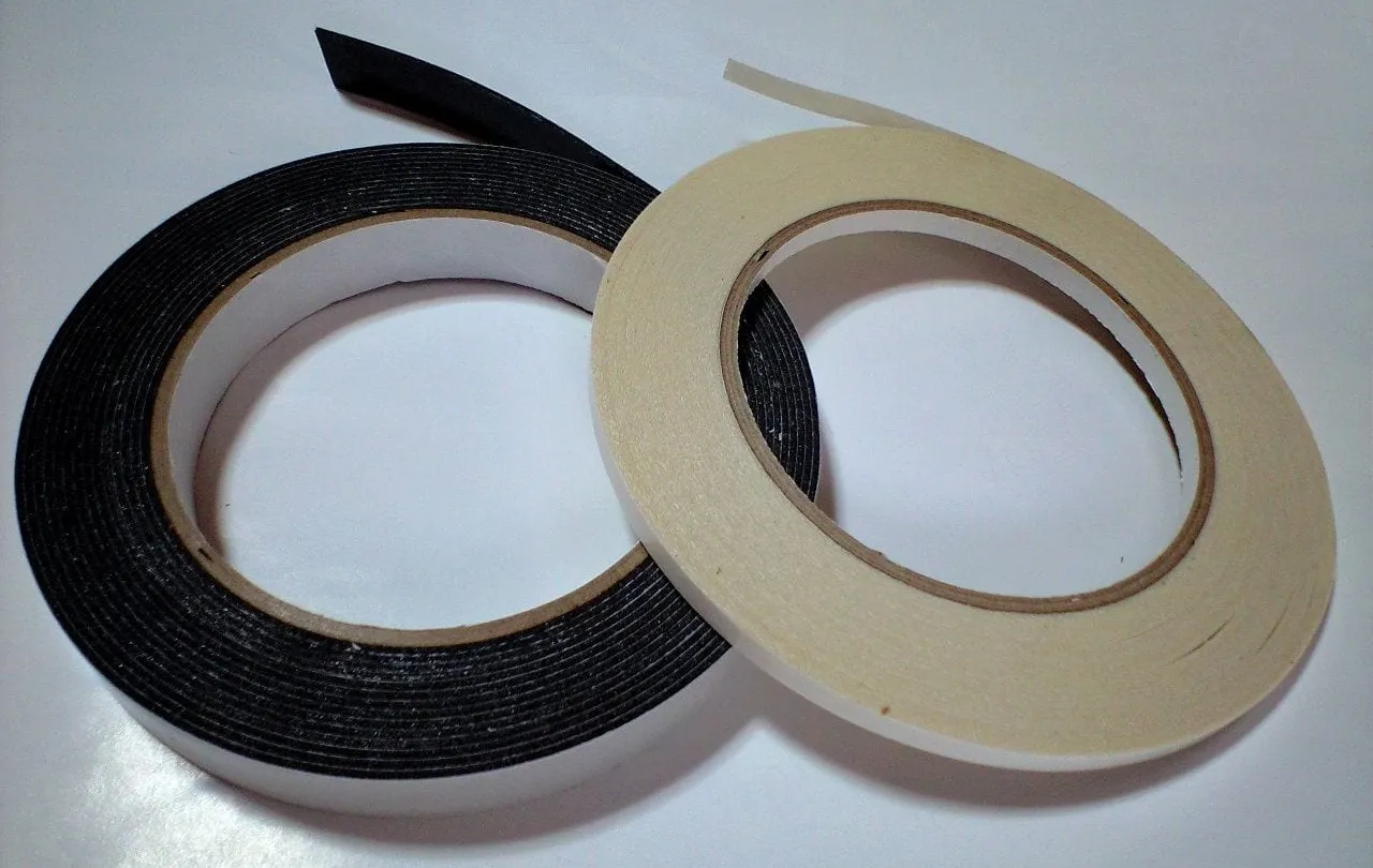 Dos rollos de cinta doble cara de espuma, uno negro y uno blanco