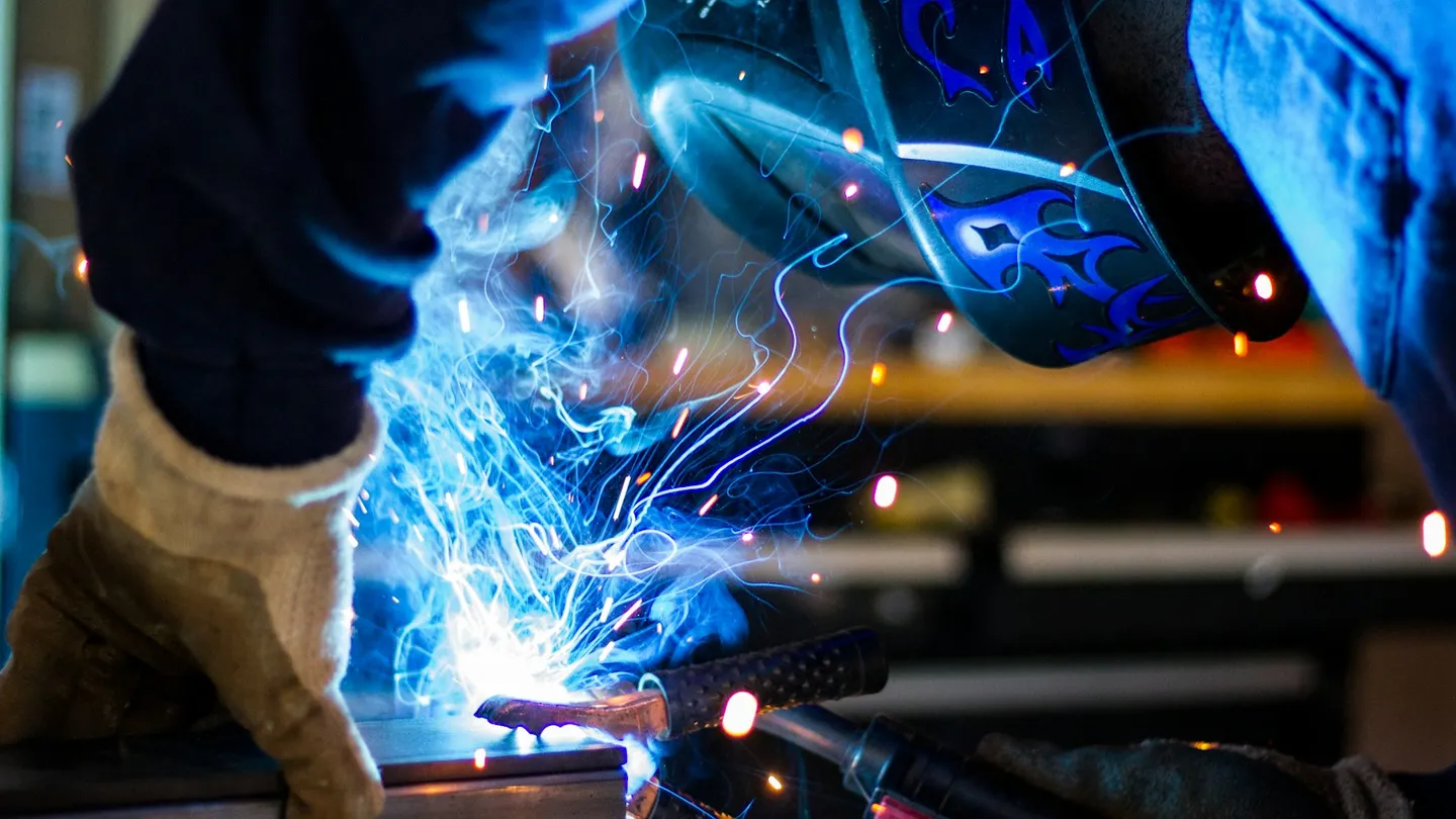 Soldador con careta y guantes trabajando