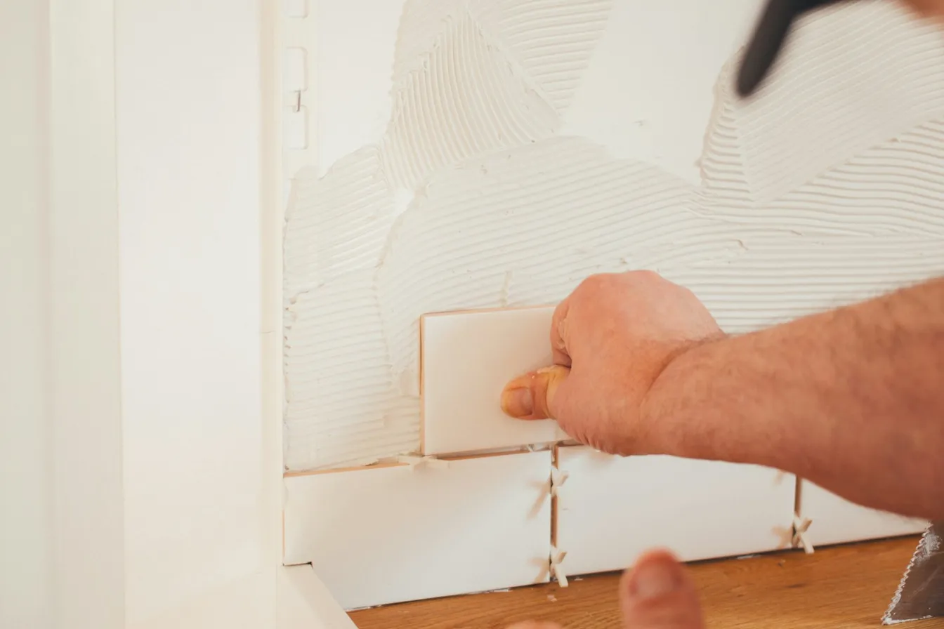 Mano colocando una pieza de azulejo en un muro