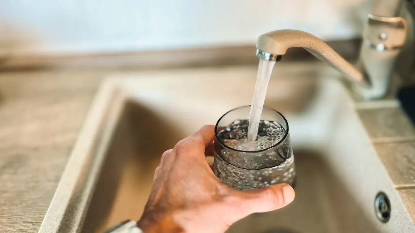 Vaso llenándose con agua de la llave de una tarja