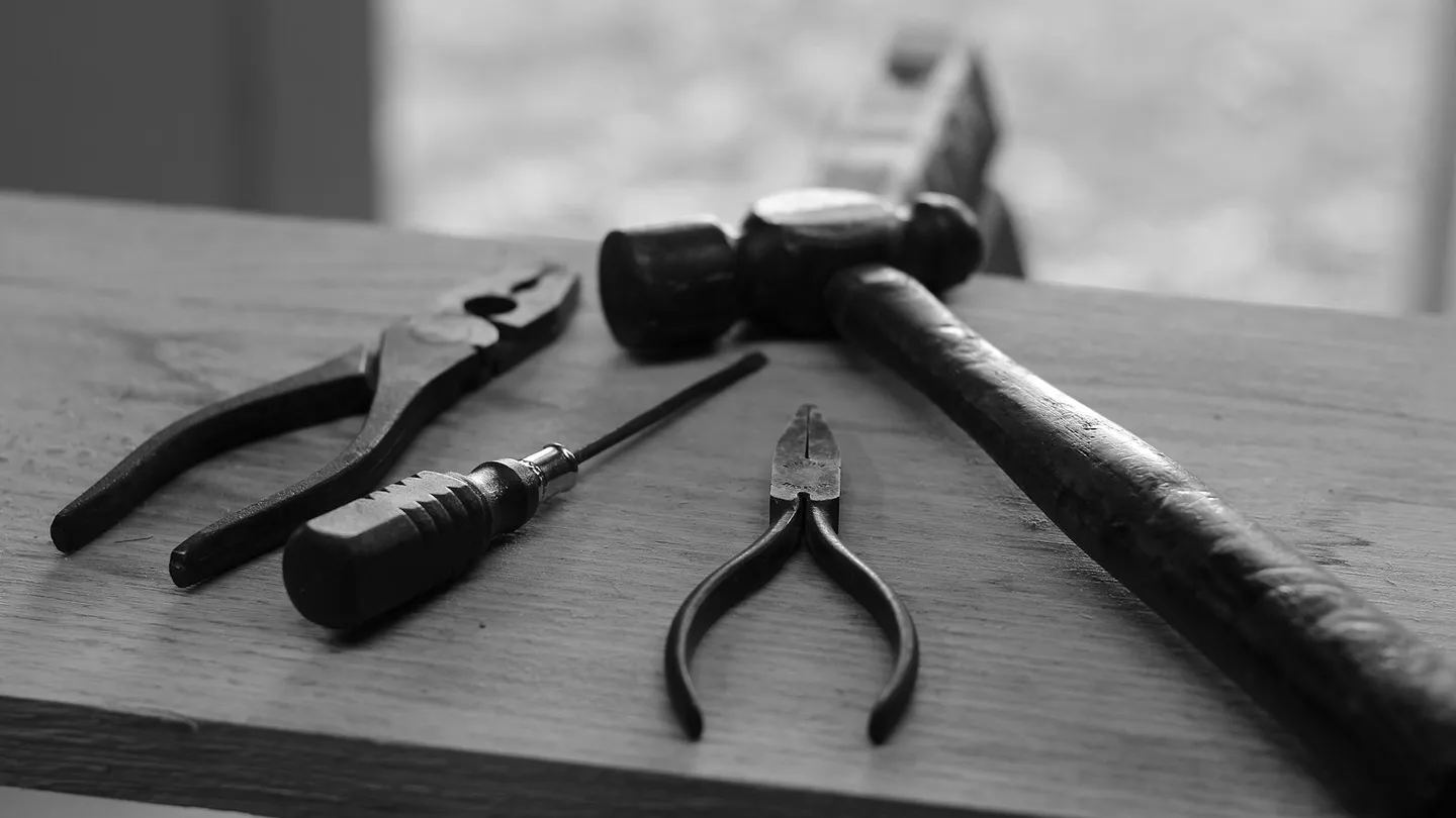 Martillo, desarmador y dos pinzas sobre una tabla de madera