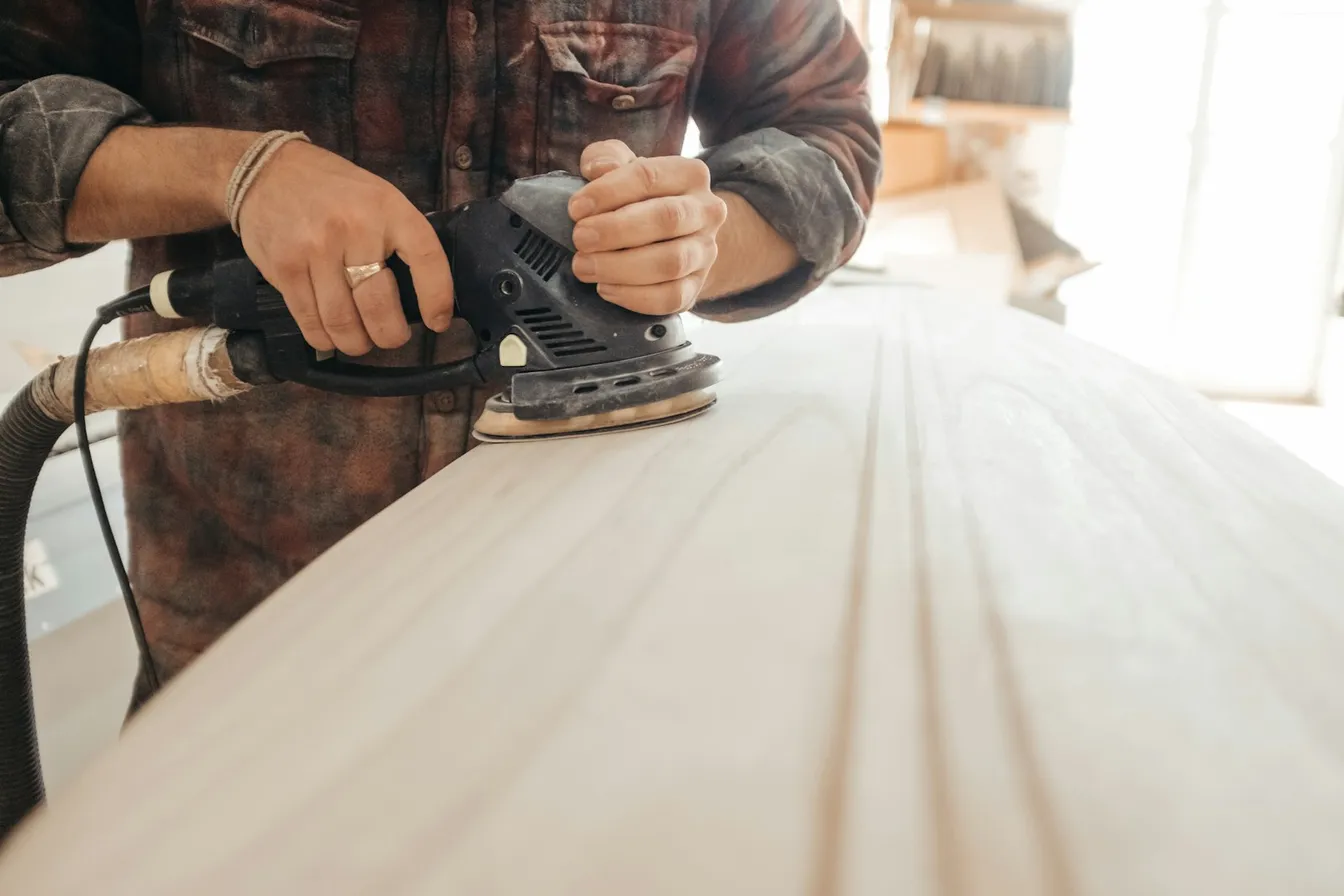 Persona lijando una superficie de madera con lijadora eléctrica