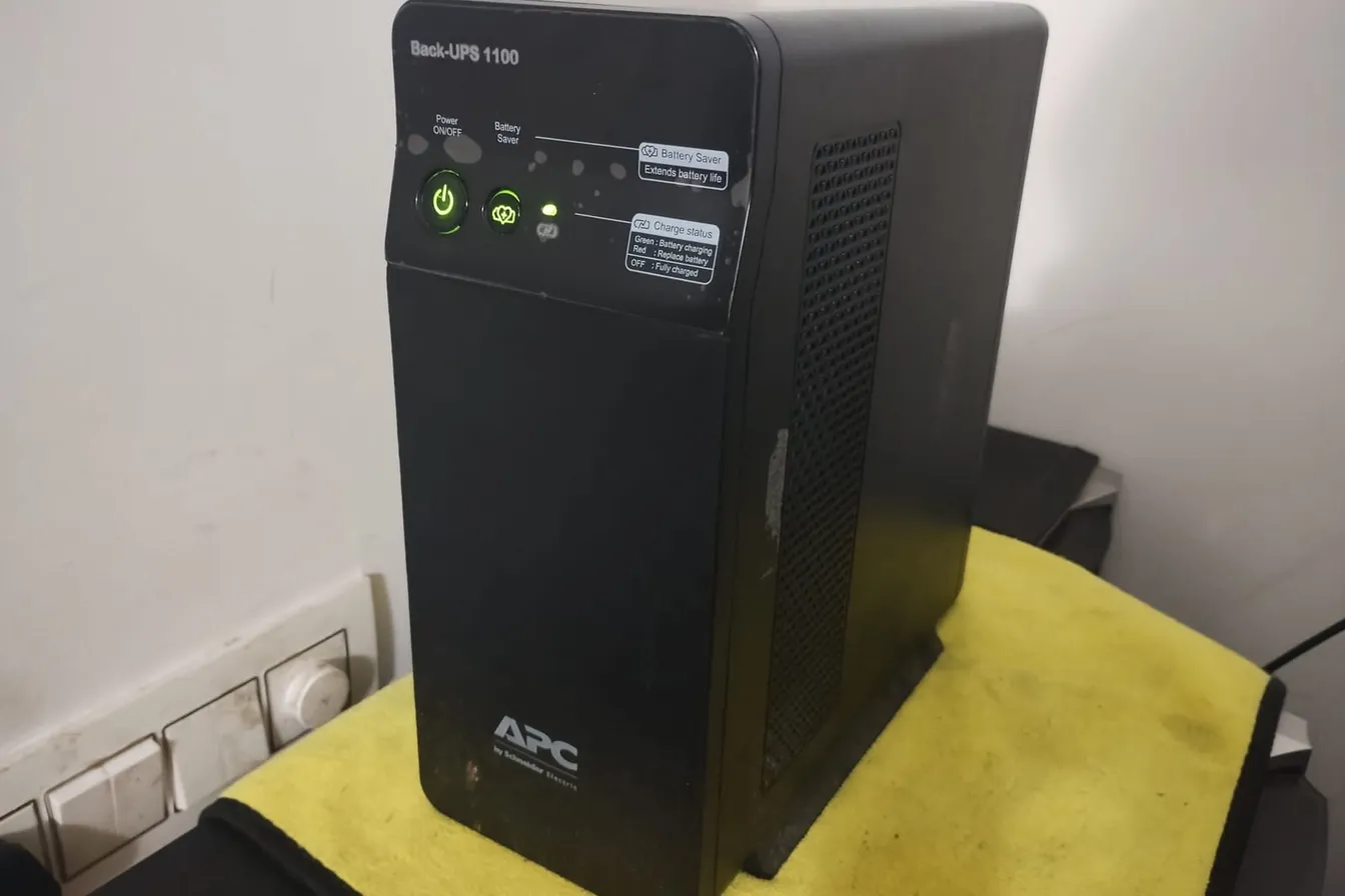 No break de torre APC de 1100 VA encendido, junto a la pared