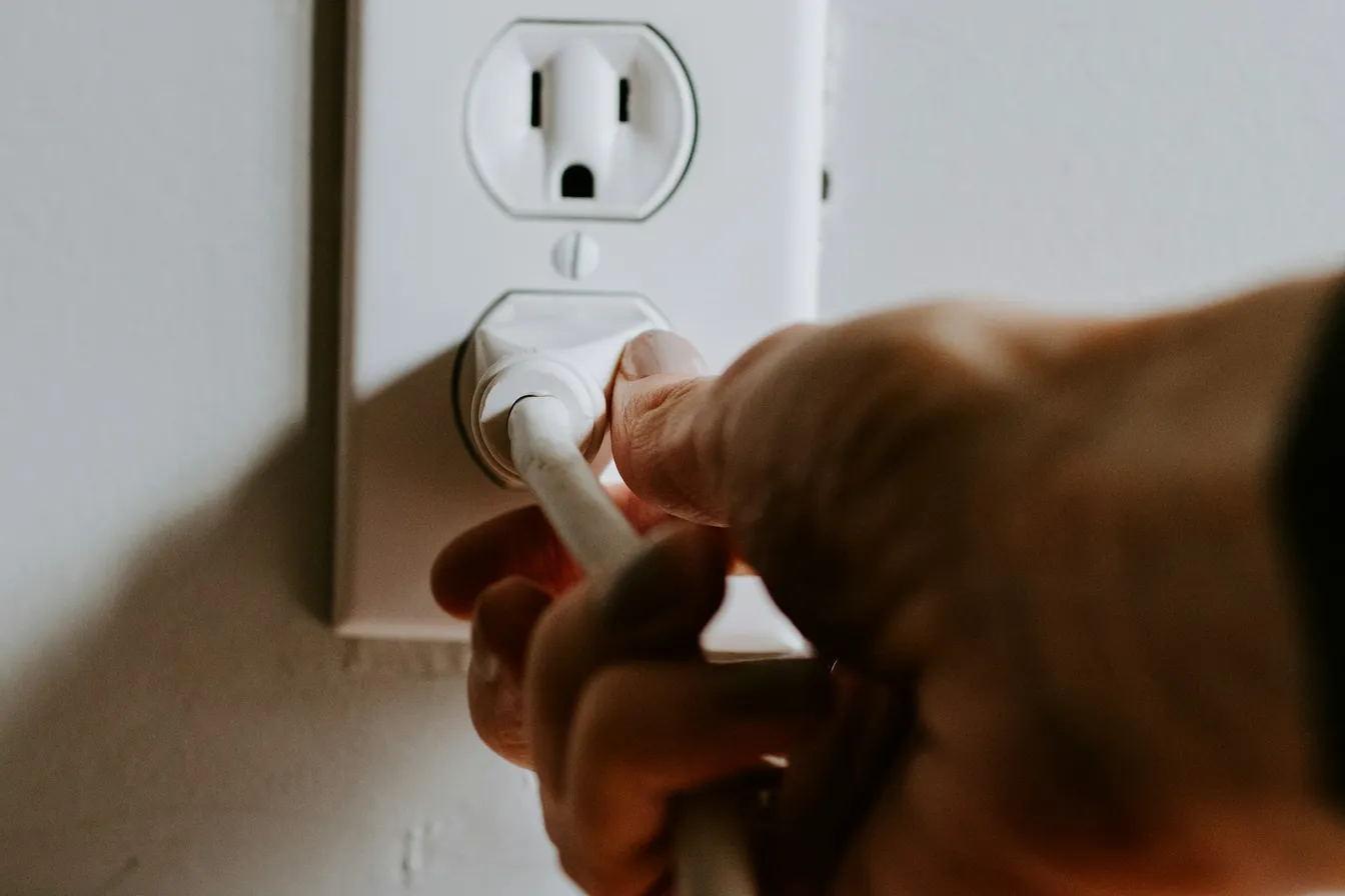 Mano conectando una clavija en un contacto de pared