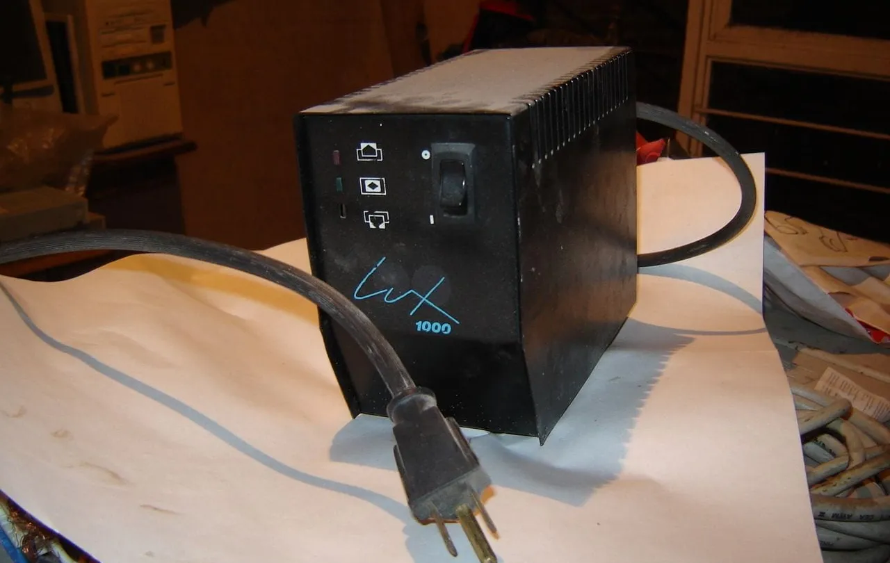 Regulador de voltaje de escritorio negro con su cable y clavija de tres patas