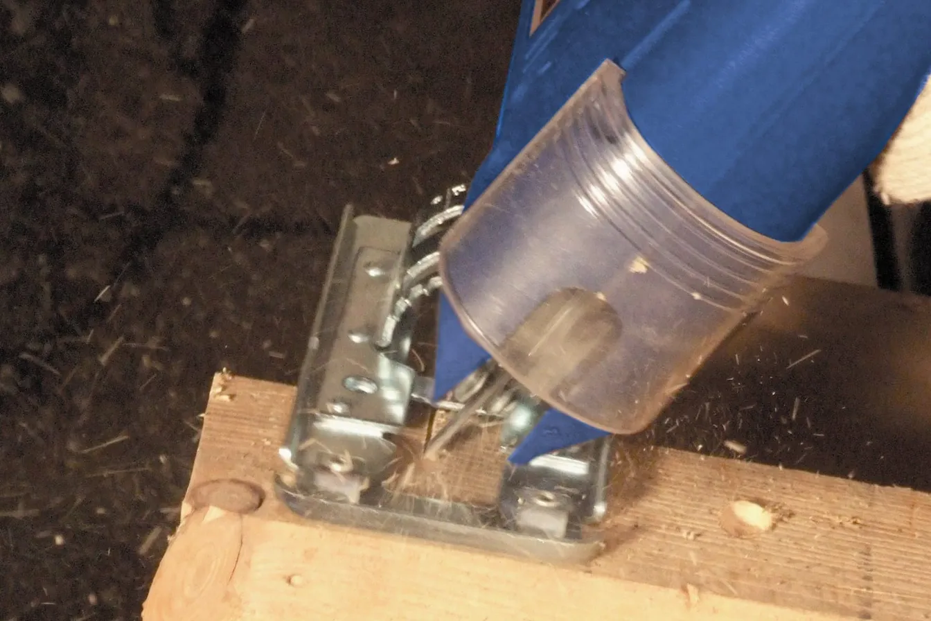 Sierra caladora con la base inclinada haciendo un corte en ángulo sobre una tabla