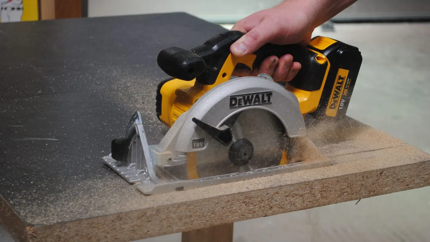 Sierra circular inalámbrica DeWalt con su guarda cortando un tablero de aglomerado