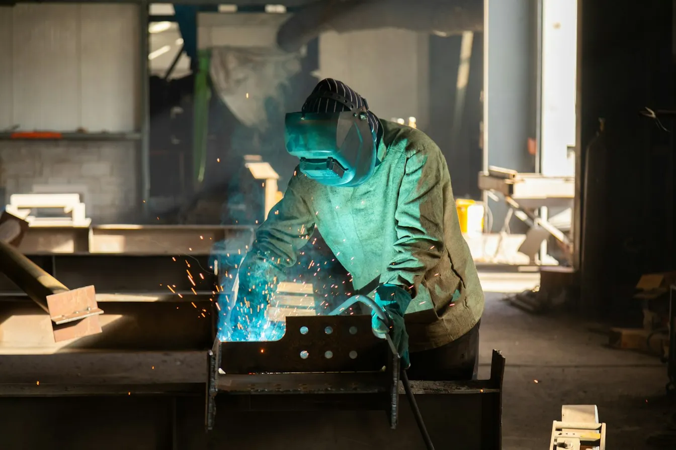 Soldador trabajando una pieza de metal en un taller