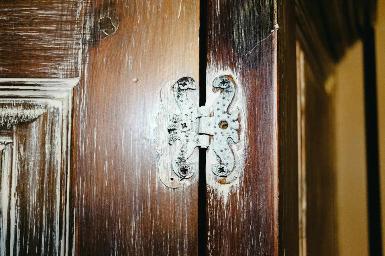 Bisagra decorativa atornillada en una puerta de madera antigua